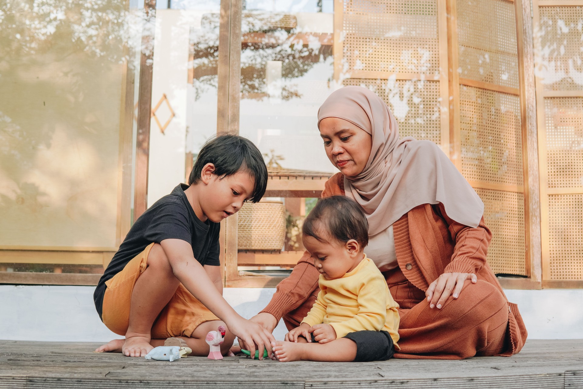 Smiling Asian Muslim mother playing with her children outside.